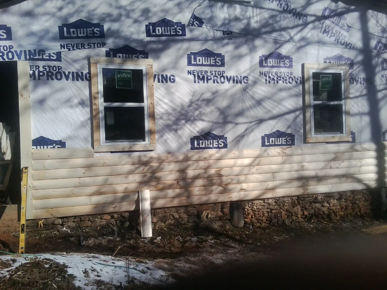 House wrap and new log siding going up on an exterior wall in Cumberland
